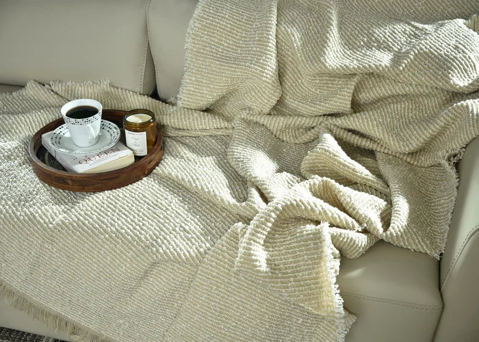 Light taupe knitted throw blanket close-up with textured knit and fringe trim