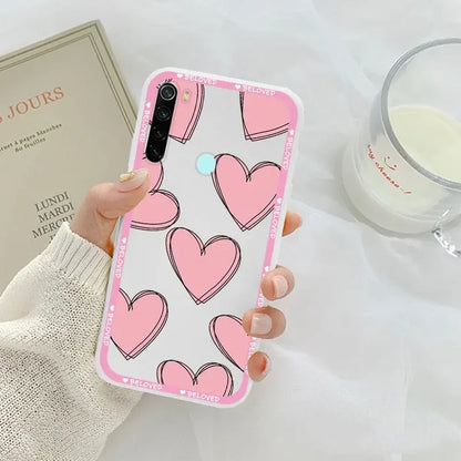 a woman holding a pink phone case with hearts on it