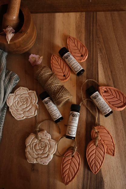 Small bottles with labels on a wooden surface with decorative elements like twine and flowers.