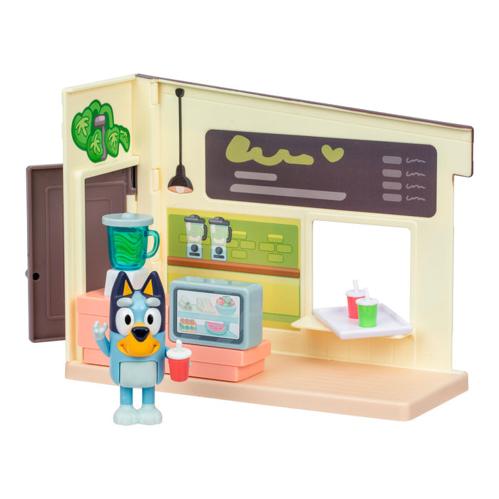 The Bluey Mini Playset & Figures by Moose Toys includes a Bluey figurine with a red cup, counter, display case, blender, and backdrop with menu—ideal for collectible playset fans.