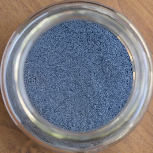 Close-up of a glass jar filled with blue powder on a wooden surface