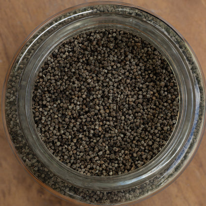 Close-up of a glass jar filled with small brown pellets on a wooden surface.