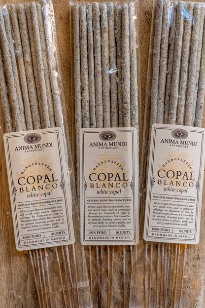 Three bundles of Anima Mundi Copal Blanco incense sticks with labels on a wooden surface.