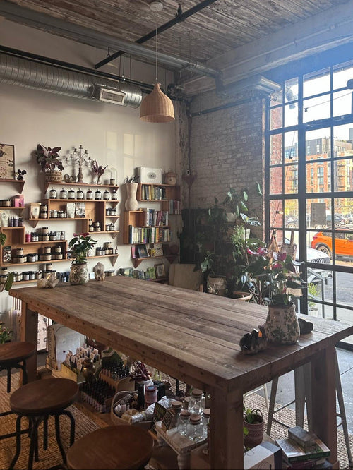 Cozy cafe interior with wooden tables, shelves, and large windows.