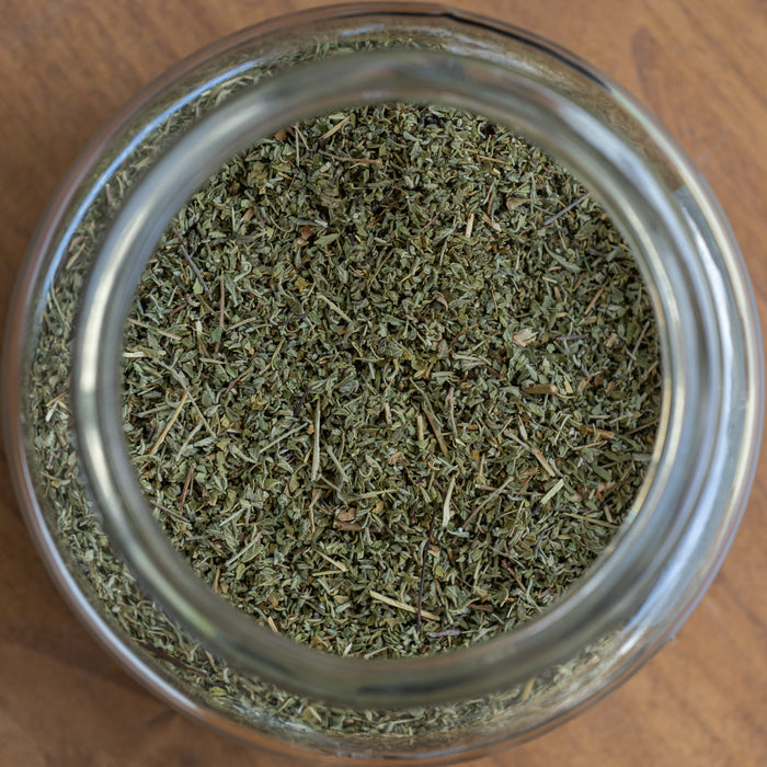 Glass jar filled with dried herbs on a wooden surface
