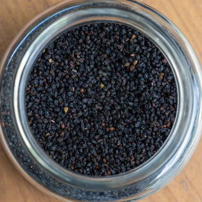 Close-up of a glass jar filled with black pepper on a wooden surface