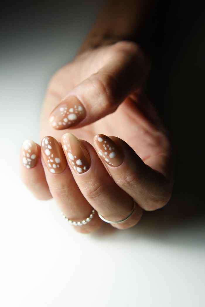 Caramel nude press-on nails with creamy white fawn spots – detail view