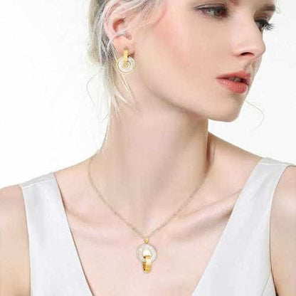 Woman wearing a gold necklace with a pendant on a white background