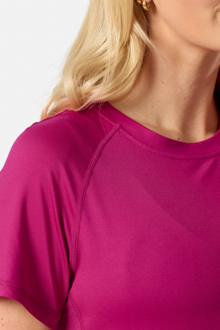 Close-up of Gym+Coffee Relentless Tee in Sunrise Pink on model, shop Gym+Coffee at Dotique for stylish activewear.
