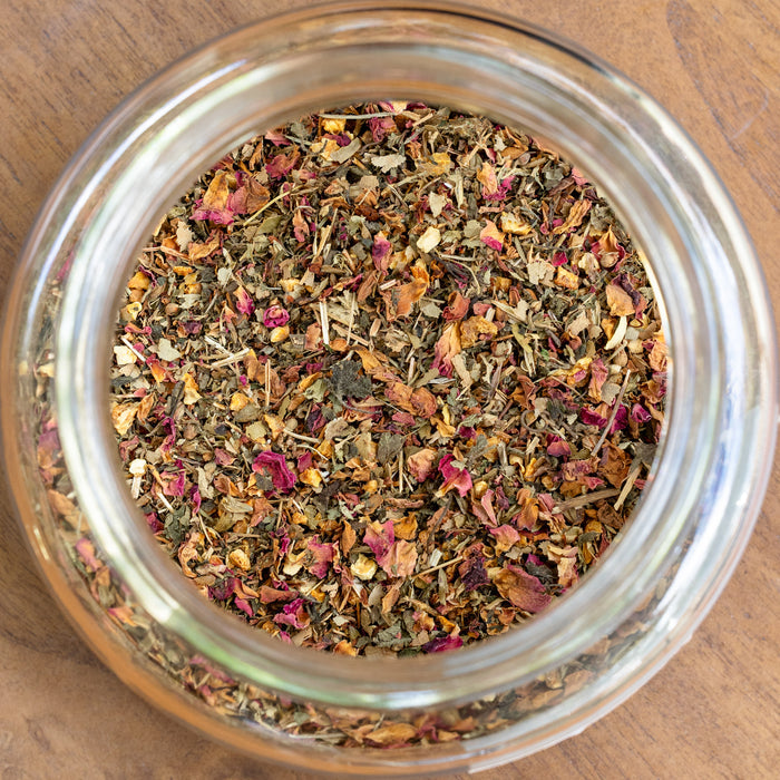 Glass jar filled with dried herbs on a wooden surface