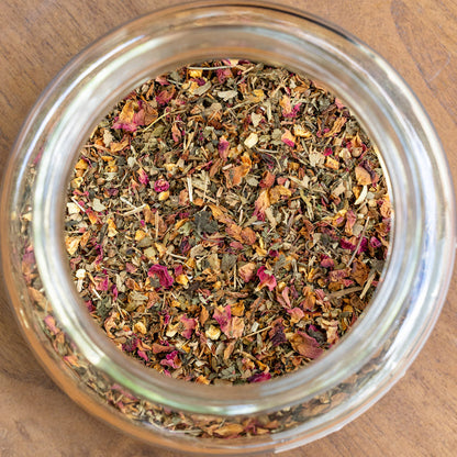 Glass jar filled with dried herbs on a wooden surface