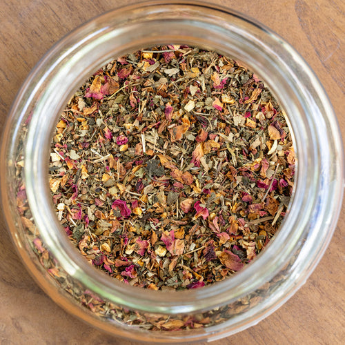 Glass jar filled with dried herbs on a wooden surface