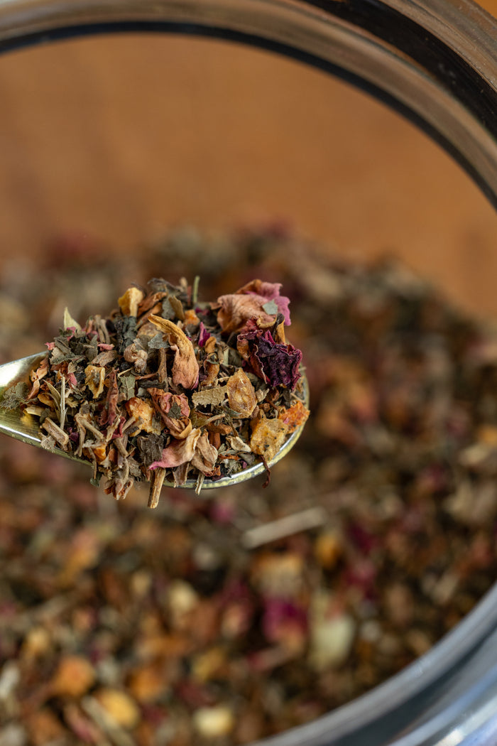 Spoonful of dried herbs over a container of mixed herbs
