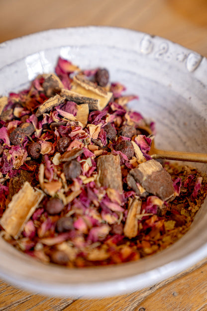 Dried herbs and spices in a white bowl on a wooden surface