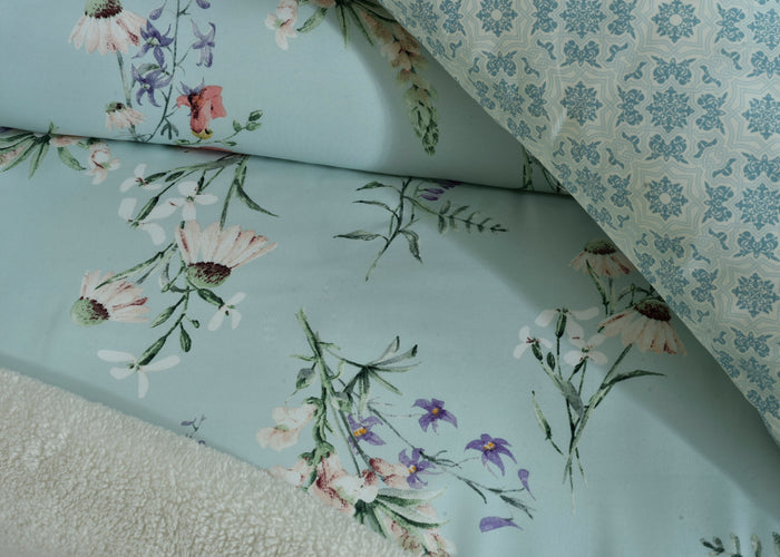 Light blue comforter close-up with detailed flower and leaf embroidery