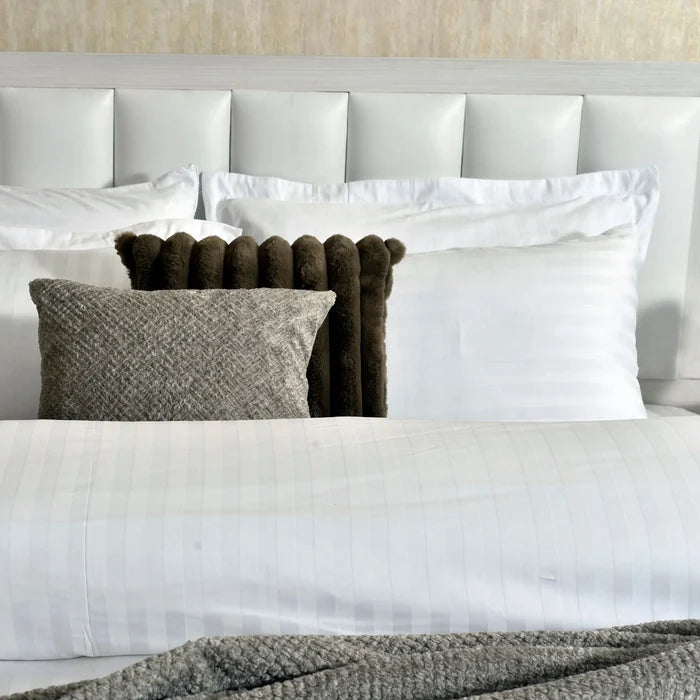 Striped duvet cover with white pillows and dark brown pom bolster cushions