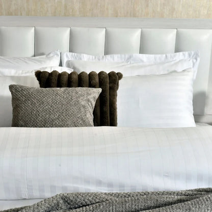 Striped duvet cover with white pillows and dark brown pom bolster cushions
