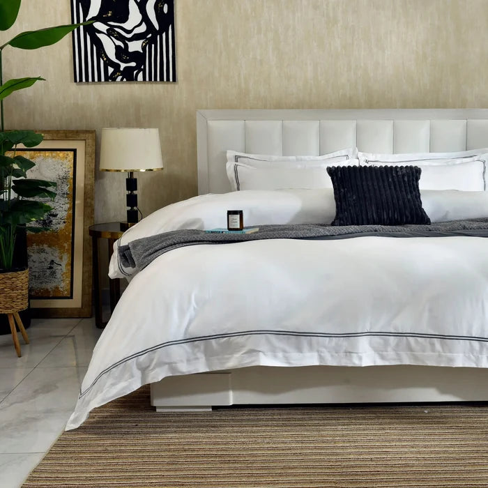 White duvet cover with black piping and navy ribbed throw pillow on bed