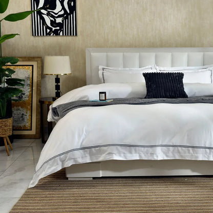 White duvet cover with black piping and navy ribbed throw pillow on bed