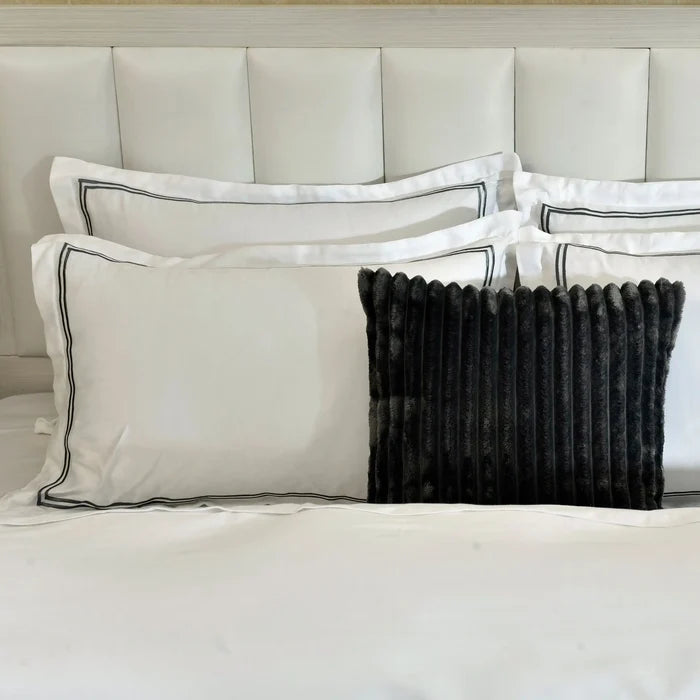 White duvet cover with black piped edge and paired navy ribbed accent pillows