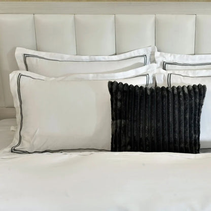 White duvet cover with black piped edge and paired navy ribbed accent pillows