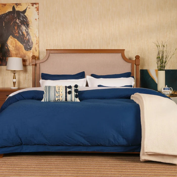 Blue duvet cover set with cream and striped pillows on bed
