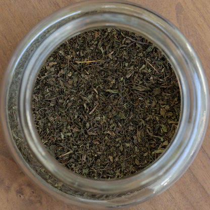 Glass jar filled with dried herbs on a wooden surface