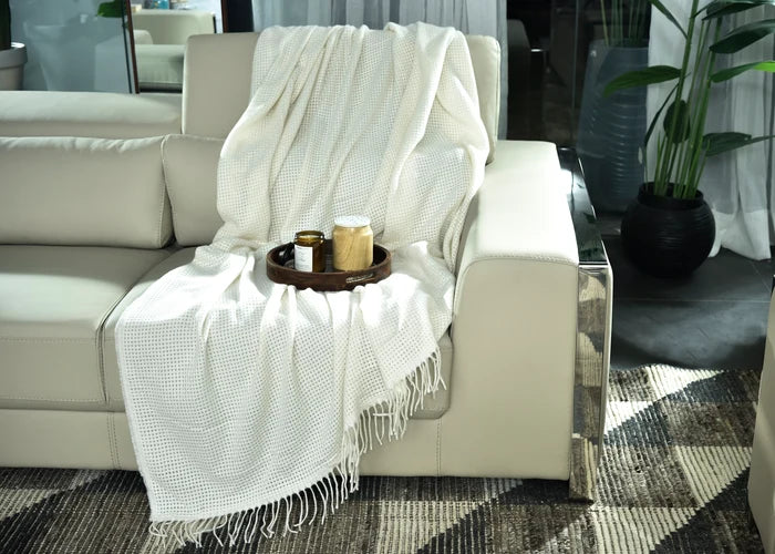 Light beige knitted throw blanket with textured pattern and fringed edge