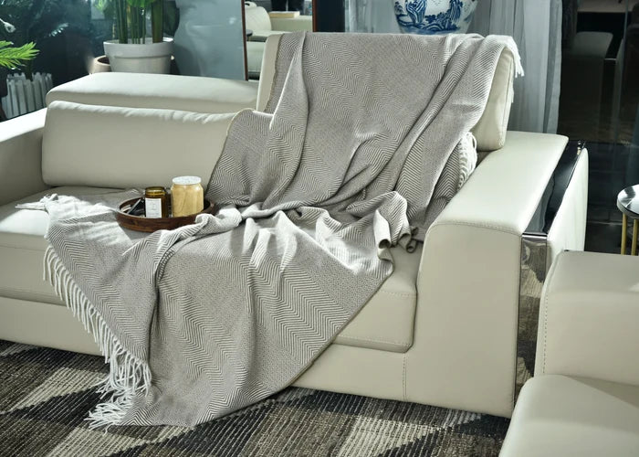 Light brown knitted throw with fringed edges, draped over sofa