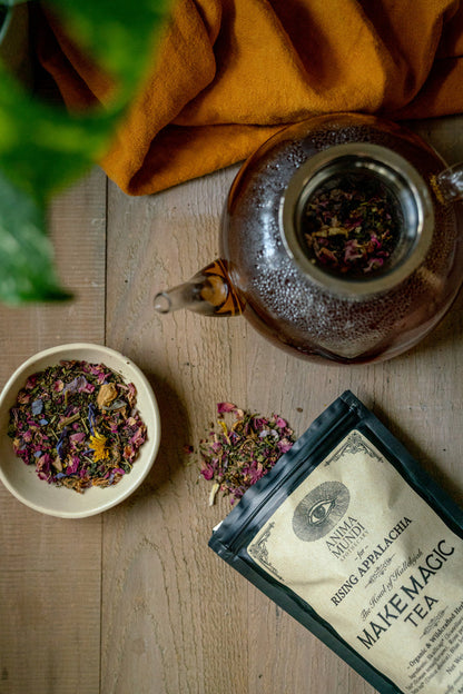 Tea-making setup with a teapot, tea leaves, and a package on a wooden surface.