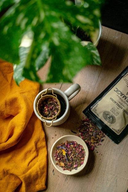 Tea-making setup with tea leaves, a tea strainer, and a yellow cloth on a wooden surface.