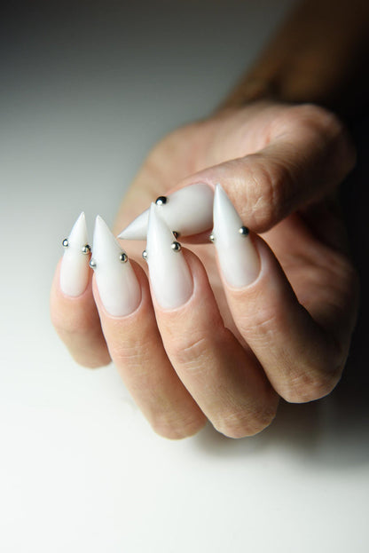 Milky white press-on nails with small metallic piercing studs