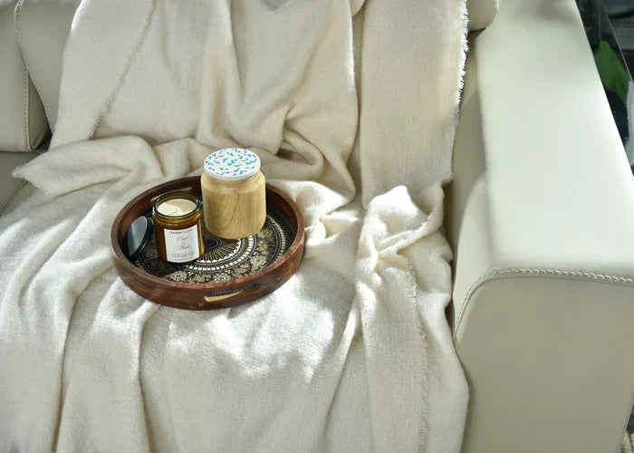 Natural knitted throw blanket close-up with fringed texture and folded corner