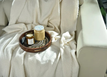 Natural knitted throw blanket close-up with fringed texture and folded corner