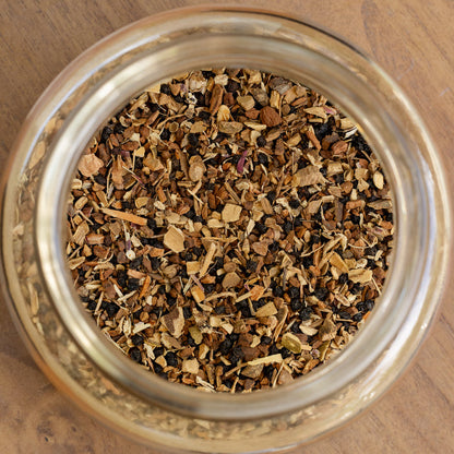 Glass jar filled with dried herbs on a wooden surface