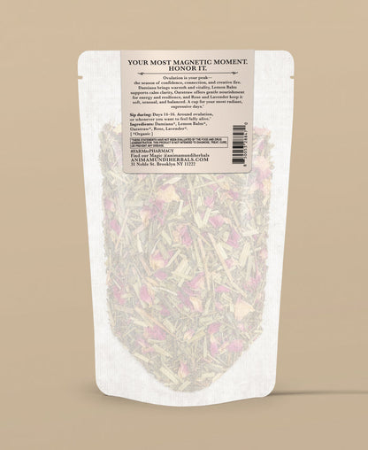 A stand-up pouch of herbal tea with a white label and clear lower section showing dried flowers and leaves inside, photographed on a solid beige background.
