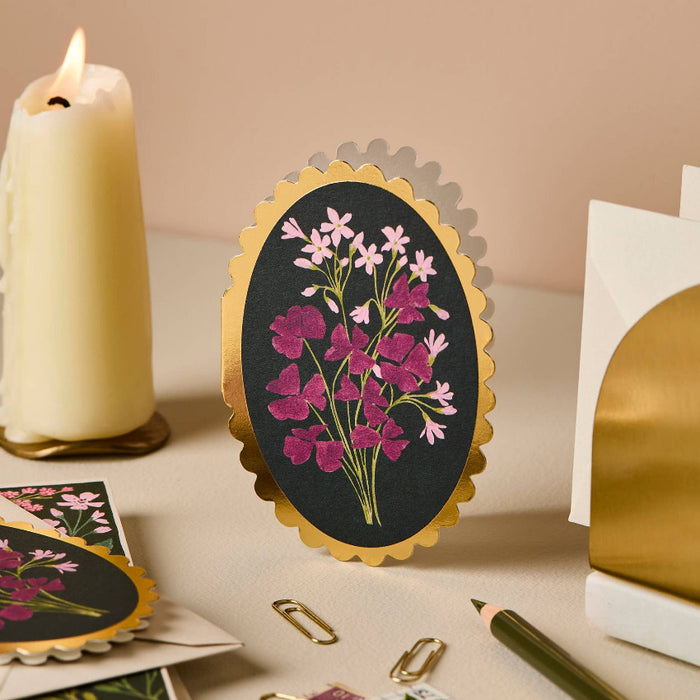 Decorative card with floral design on a table with a candle and other items.