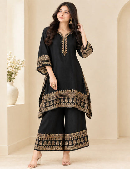 Model posing in an elegant black kaftan and palazzo set with detailed gold foil printing and embroidery against a neutral background.