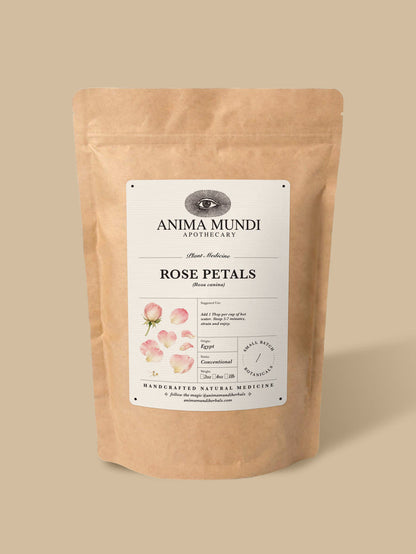 A stand-up kraft paper pouch of Anima Mundi Apothecary Rose Petals, featuring a white label with pink rose illustrations, set against a solid beige background.
