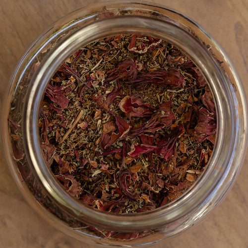 Glass jar filled with dried herbs on a wooden surface