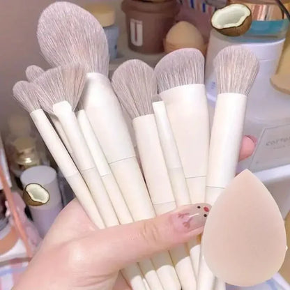 Set of makeup brushes held by a hand with a blurred background. Soft fluffy makeup brush set with wool fiber bristles and plastic handles. Complete set for powder, foundation, eyeshadow, and beauty blending.