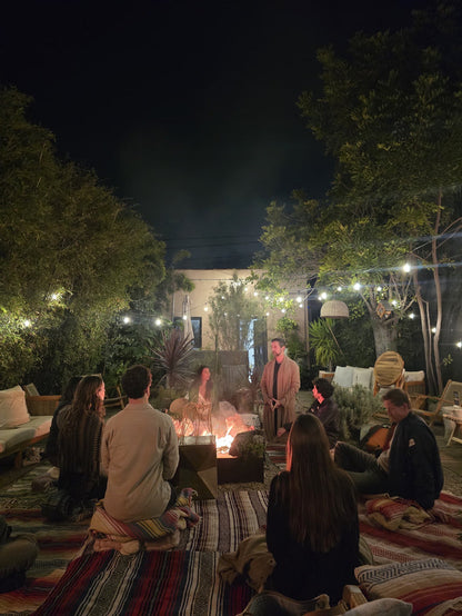 People gathered around a fire pit in a garden setting at night.