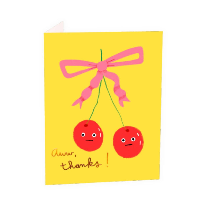 Greeting card with two red cherries and a pink bow on a yellow background