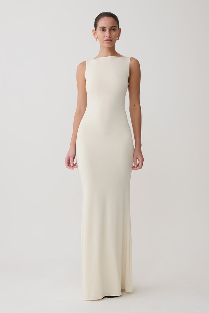 Woman wearing a long, off-white dress against a plain background
