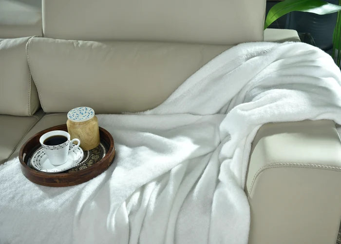 White knitted throw blanket, folded on sofa armrest with textured knit surface