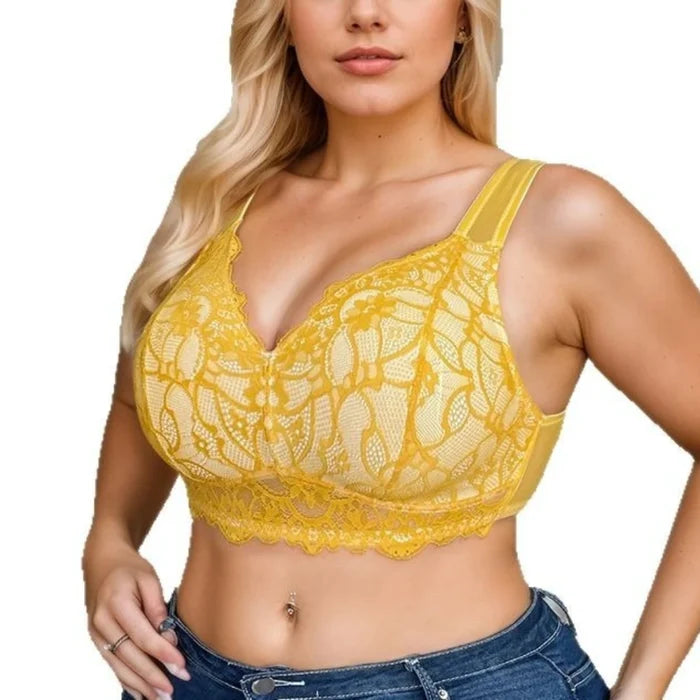 A woman wearing a yellow lace underwire bralette with wide shoulder straps and a scalloped lace hem, paired with blue jeans against a plain white background.