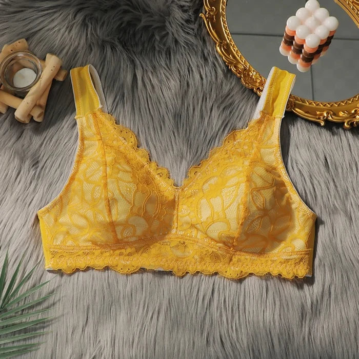 Yellow lace bra on a textured surface with decorative elements.