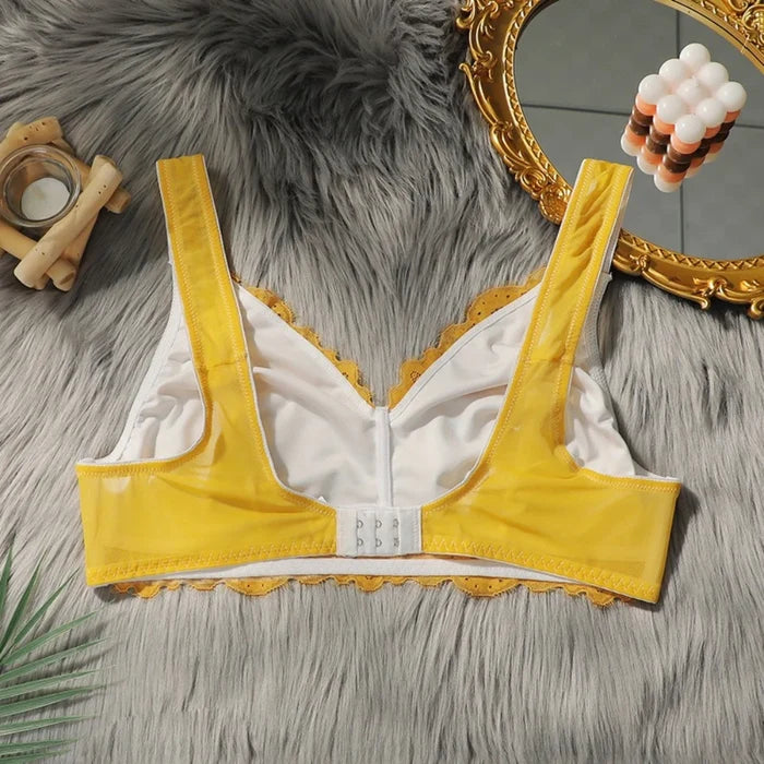 Yellow bra with lace trim on a textured surface