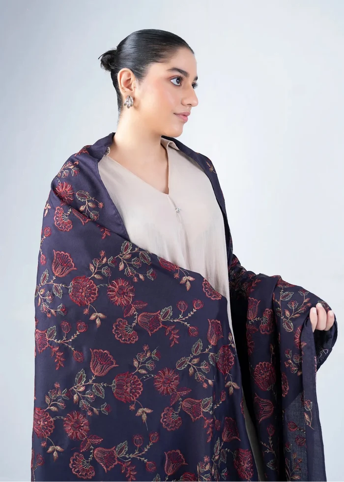 Women's wool winter shawl in dark navy with burgundy floral pattern, draped on shoulders
