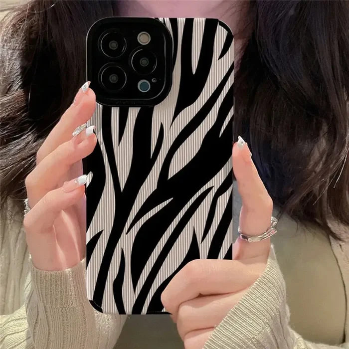 A woman holding up her phone case with zebra print